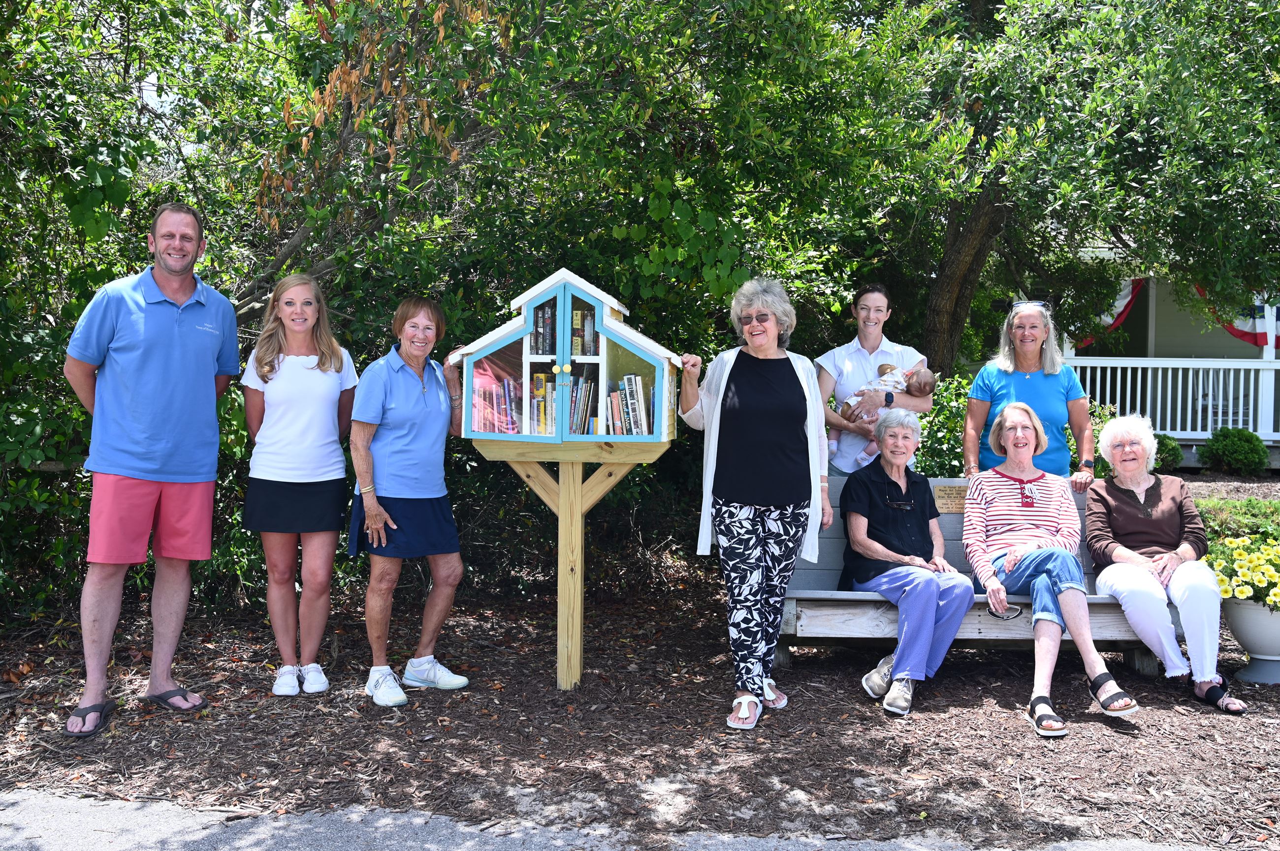 A group of women and one man surround a mini library
